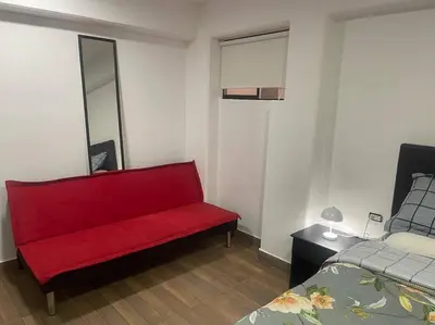 a red bench in a room with a bed at (26) Departamento cómodo y tranquilo en Miraflores in Lima