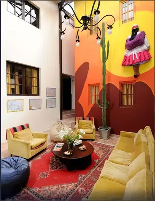 a living room with yellow furniture and a cactus painted on the wall at Bear Packer Hostel in Cusco
