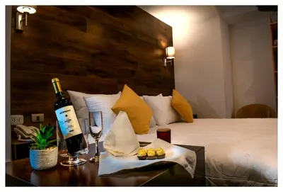 a bottle of wine on a table next to a bed at LA TERRAZA INN in Huancavelica