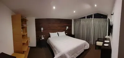 a bedroom with a large white bed and a chair at LA TERRAZA INN in Huancavelica