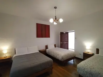 a bedroom with two beds and a chandelier at El Jardín de Jeni in Cusco
