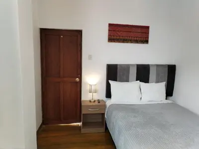 a bedroom with a bed and a wooden door at El Jardín de Jeni in Cusco