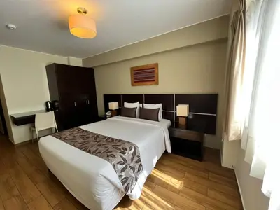 a bedroom with a large white bed and a desk at Hotel El Tambo 2 in Lima