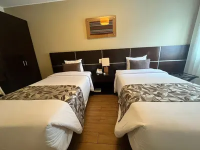 a hotel room with three beds and a window at Hotel El Tambo 2 in Lima