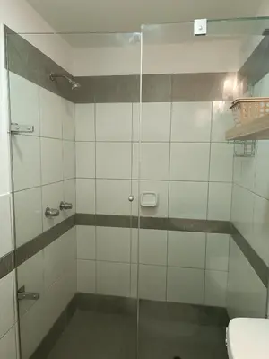 a bathroom with a glass shower with a toilet at Runawasi Apartments - Amaru 3BDR in Lima
