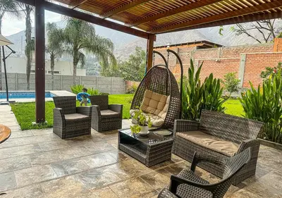 a patio with wicker chairs and a table at KUSI WASI CIENEGUILLA in Cieneguilla