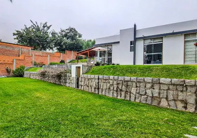 a stone retaining wall in front of a house at KUSI WASI CIENEGUILLA in Cieneguilla