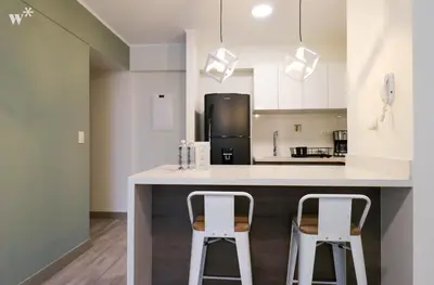a kitchen with two white stools at a kitchen counter at The Classic by Wynwood House in Lima
