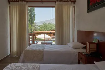 a hotel room with two beds and a large window at El Molino Hotel y Restaurant in Lunahuaná