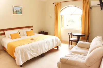 a bedroom with a bed and a chair and a window at Lunahuana River Resort in Lunahuaná