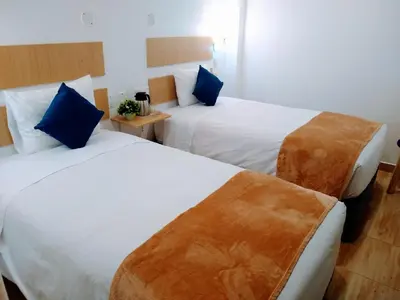 two beds in a hotel room with blue pillows at Emmanuel inn Machupicchu in Machu Picchu