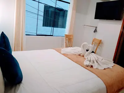 a bedroom with a bed with white sheets and a window at Emmanuel inn Machupicchu in Machu Picchu