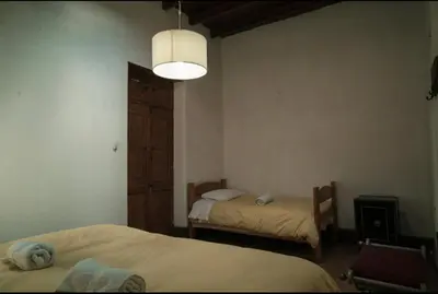 a bedroom with two beds and a light fixture and a room with two beds at Refugio de Santiago Ecolodge in Lunahuaná