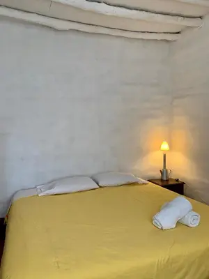 a yellow bed with two pillows and a lamp at Refugio de Santiago Ecolodge in Lunahuaná