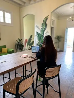 a woman sitting at a table with a laptop at Ancestral Hostel Barranco in Lima