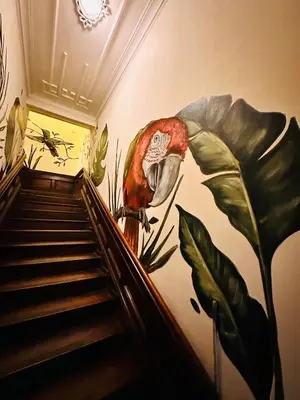 a mural of a parrot on a wall next to stairs at Ancestral Hostel Barranco in Lima