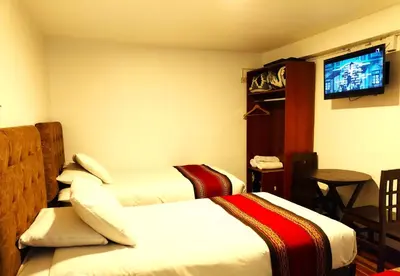 a hotel room with two beds and a flat screen tv at Paqarina San Blas in Cusco