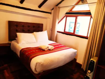 a teddy bear laying on a bed in a bedroom at Paqarina San Blas in Cusco