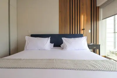 a large bed with white sheets and pillows at Mimosas 145 by Wynwood House in Lima