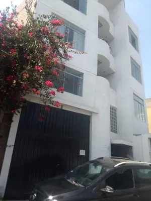 a black car parked in front of a white building at RESIDENCIAL SALAMANCA in Lima