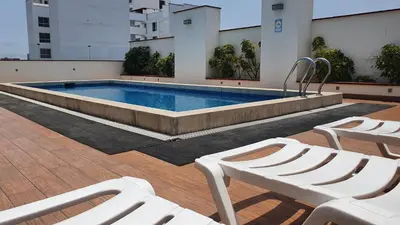 a swimming pool with white lounge chairs in front of a building at Hermoso departamento amoblado con piscina, area parrillas in Lima