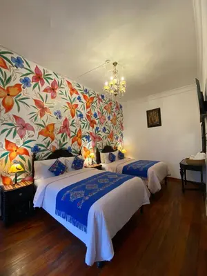 a bedroom with two beds and a floral wall at Casona Dorada Hotel Cusco in Cusco