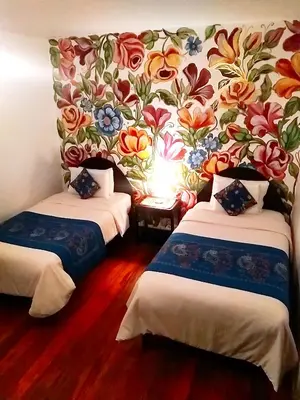 a room with two beds with a floral wallpaper at Casona Dorada Hotel Cusco in Cusco