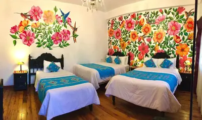 three beds in a room with a mural of flowers at Casona Dorada Hotel Cusco in Cusco
