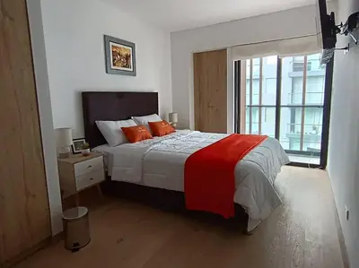 a bedroom with a bed with orange pillows and a window at Runawasi Apartments - Killary Miraflores 2BDR in Lima