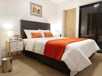 a bedroom with a large bed with orange pillows at Runawasi Apartments - Killary Miraflores 2BDR in Lima
