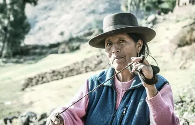 an older woman wearing a hat talking on a phone at Refugio Viñak in Viñak