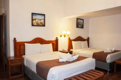 a hotel room with two beds with white sheets at Hotel Amerinka in Cusco