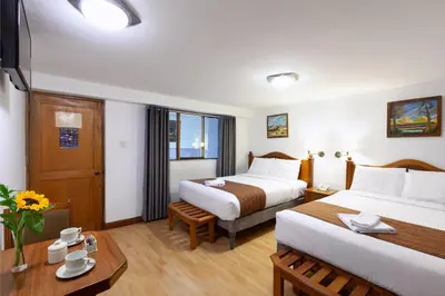 a hotel room with two beds and a table at Hotel Amerinka in Cusco