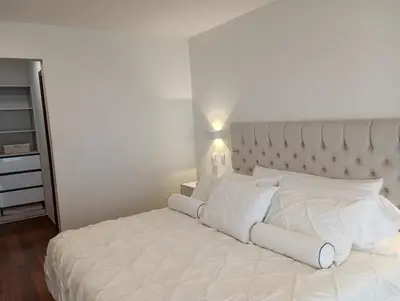 a white bed with white pillows in a bedroom at EL PRAT Luxury Aparment Lima Peru in Lima