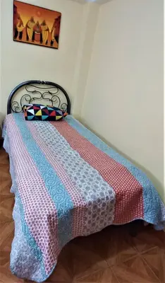 a bed with a colorful blanket on top of it at Carlos Guest House 2 Cusco in Cusco