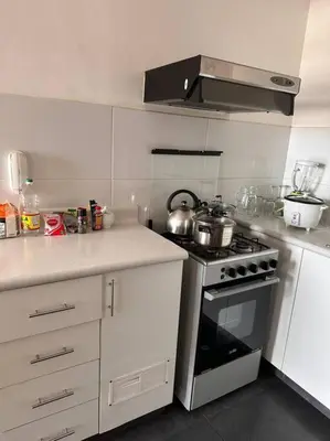a kitchen with a stove and white cabinets at Lindo Departamento en Av. Guardia Civil 861 - Chorrillos in Lima