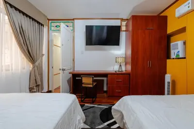 a bedroom with two beds and a desk with a television at Lima Virreinal & primer piso muy acogedor in Lima