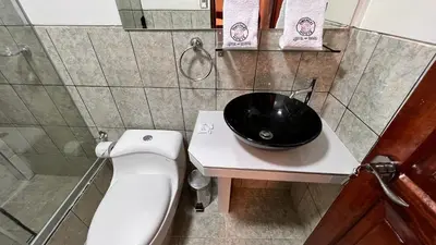 a bathroom with a toilet and a black bowl on a sink at QUECHUA´S HOUSE Hostal & Coffee in Machu Picchu