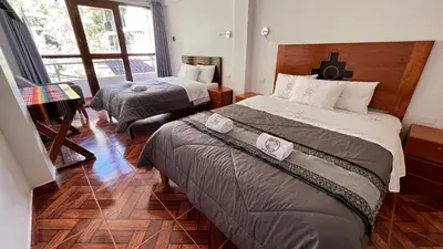 a hotel room with two beds and a window at QUECHUA´S HOUSE Hostal & Coffee in Machu Picchu