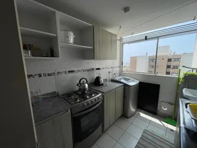 a kitchen with a stove and a sink and a window at Lindo y Acogedor Departamento en Lima! in Lima