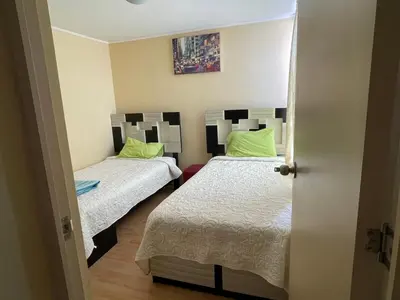 two beds in a small room with green pillows at Lindo y Acogedor Departamento en Lima! in Lima