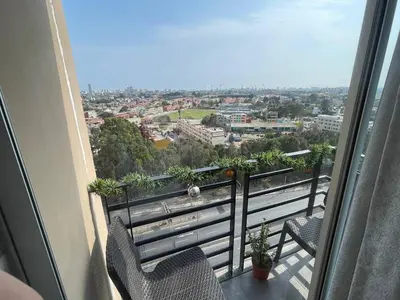 a balcony with two chairs and a view of a city at Lindo y Acogedor Departamento en Lima! in Lima