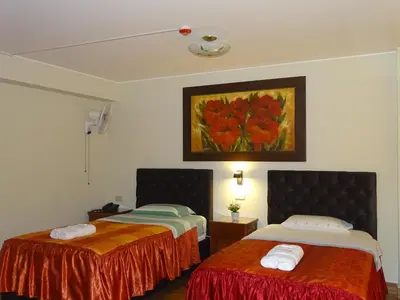 a room with two beds and a painting on the wall at Hospedaje Dimar Inn in Lima