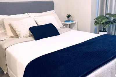 a bed with a blue and white blanket on it at Loft céntrico San borja - San Isidro in Lima
