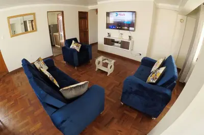 a living room with two blue chairs and a television at Centric & cozy apartment with Garage in Cusco