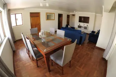 a dining table and chairs in a living room at Centric & cozy apartment with Garage in Cusco