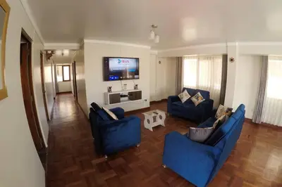 a living room with blue couches and a flat screen tv at Centric & cozy apartment with Garage in Cusco