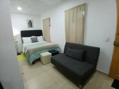 a bedroom with a bed and a couch and a chair at Centric, private, petfriendly budget apartments in Miraflores in Lima