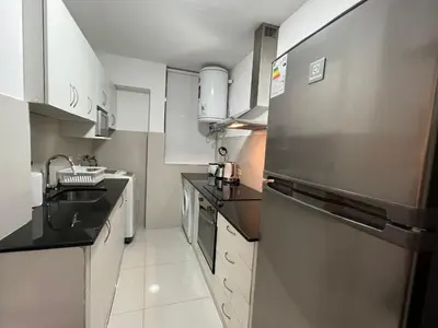a kitchen with a stainless steel refrigerator and white cabinets at San Isidro Olivar 2 bedroom Apartment in Lima
