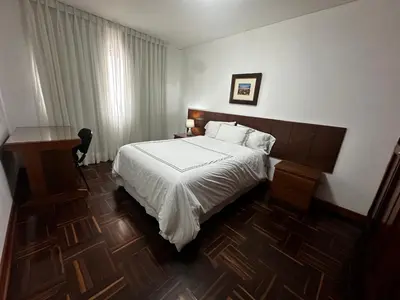 a bedroom with a white bed and a desk and a table at San Isidro Olivar 2 bedroom Apartment in Lima